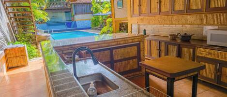 Una cocina con un lavamanos integrado, una mesa de madera y vistas a una piscina.