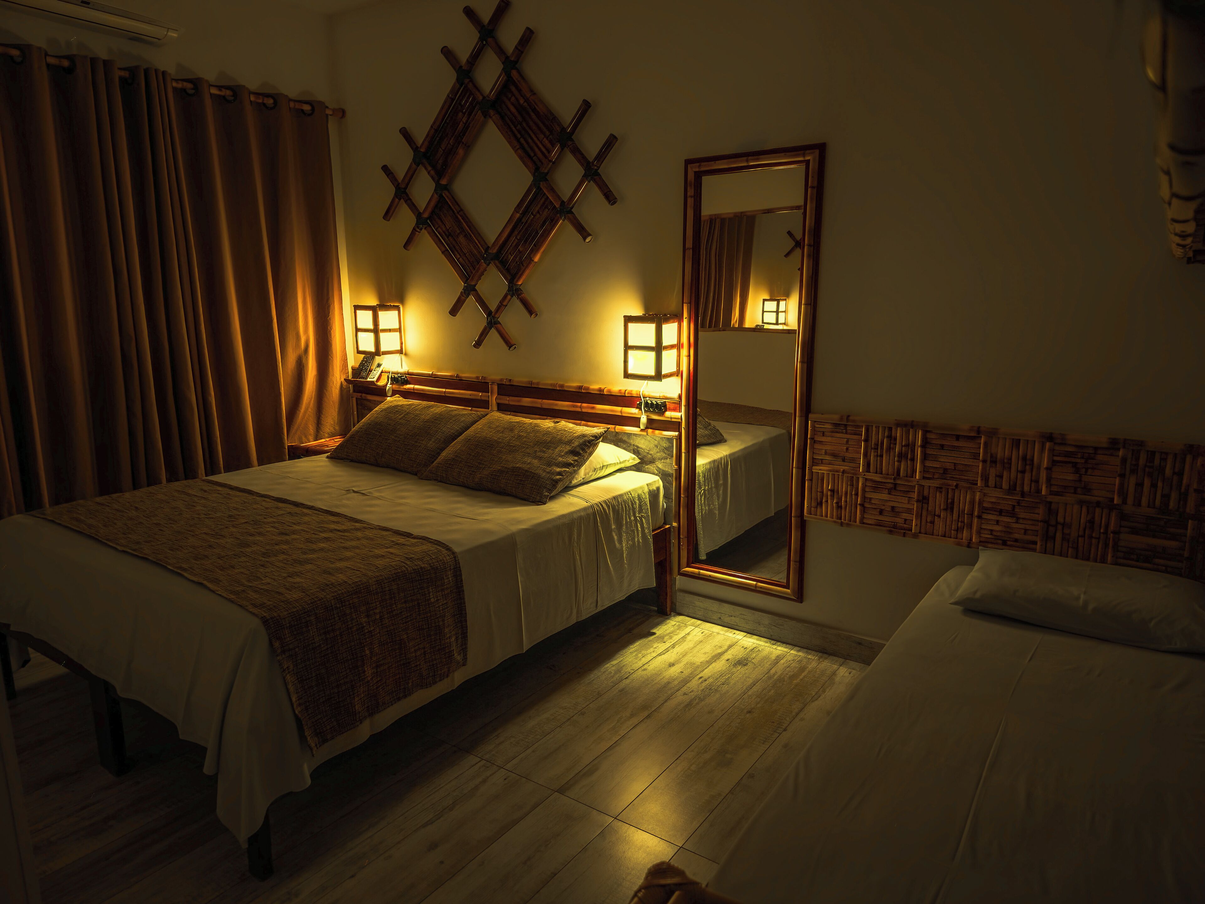 Een hotelkamer met een groot bed, bedlampen, een spiegel en een houten hoofdbord.