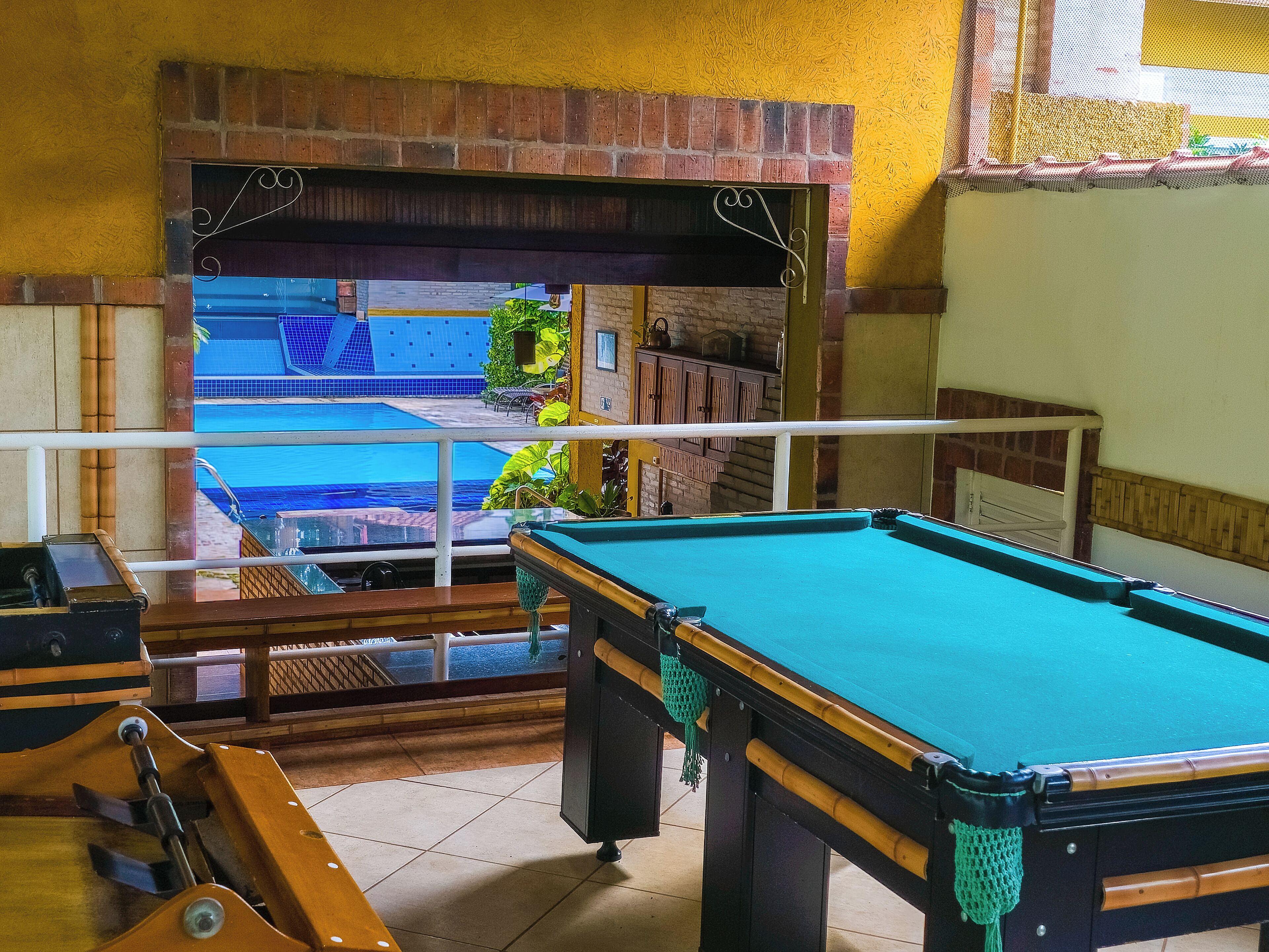 Une table de billard dans une pièce donnant sur une piscine.