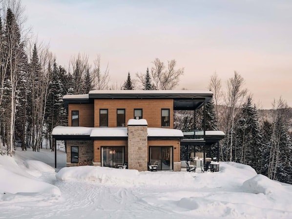 A modern two-story house with a brick facade, large windows, and a covered outdoor area. - Chalet Gratitude | Private SPA & Sauna | Skiing (Saint-Côme)