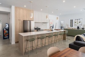 Une cuisine moderne dotée d’un îlot central, de tabourets de bar et d’un coin repas avec une table et des chaises.