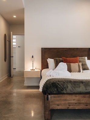 A bedroom with a wooden bed, white bedding, and a bedside table with a lamp. - Chalet Gratitude | Private SPA & Sauna | Skiing (Saint-Côme)