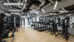 Ett gym med olika typer av träningsutrustning, inklusive löpband och styrketräningsmaskiner, och ett trägolv.