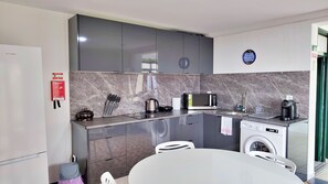 A compact kitchen with a microwave, coffee maker, and a washing machine.
