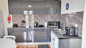 A modern kitchen with a built-in microwave, kettle, and coffee maker.