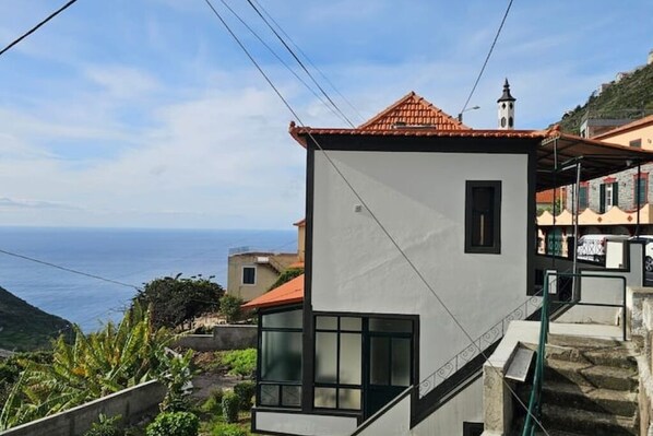 A modern building with a red-tiled roof, a small balcony, and a view of the sea. - Villa Rodrigues 2 by Rentallido (Campanario)