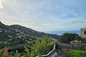 A coastal village with houses on a hillside, a road, and a view of the sea. - Villa Rodrigues 2 by Rentallido (Campanario)