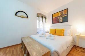 A bedroom with a bed, a bench, a painting, and a window with plants. - Shalimar House Navona by Ghor (Rome)