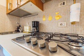 Eine Küche mit Gaskochfeld, Kaffeemaschine und einer Wand mit Kaffeetassen-Illustrationen.