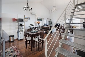 Un salón amplio con una mesa de comedor, sillas, una escalera y vistas al exterior.