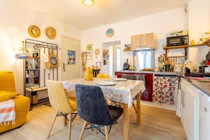 Une cuisine compacte comprenant un coin repas, un four à micro-ondes, une cuisinière et un petit réfrigérateur.