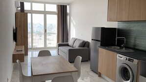 Un appartement moderne comprenant un coin repas, un canapé, une cuisine et de grandes fenêtres.