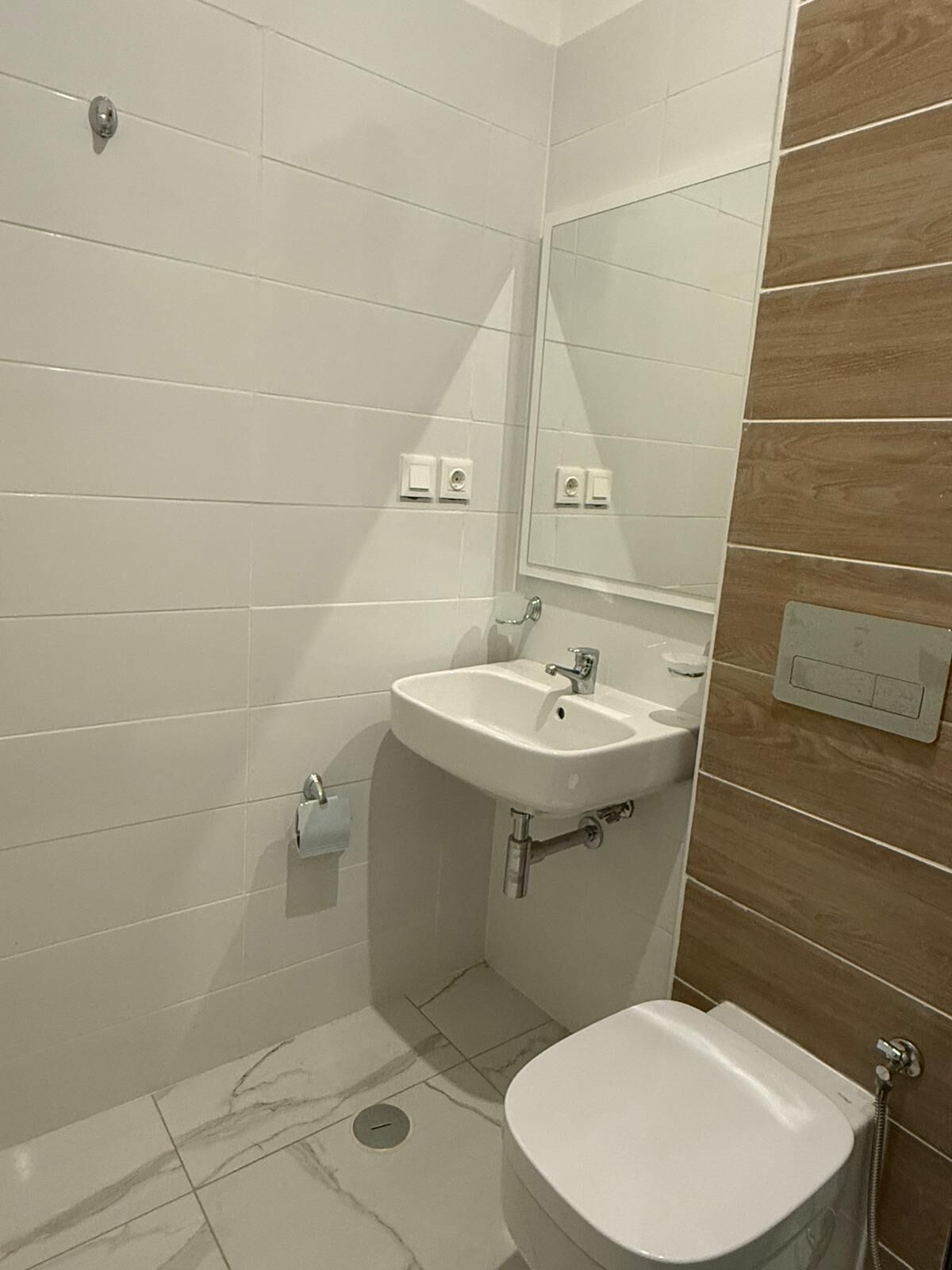A bathroom with a white sink, a mirror, and a toilet.
