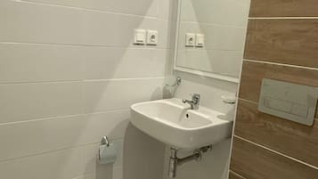 A bathroom with a white sink, a mirror, and a toilet.