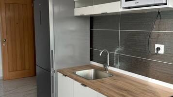 Une cuisine moderne équipée d’un réfrigérateur en acier inoxydable, d’un four à micro-ondes et d’un évier avec un plan de travail en bois.