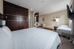 A hotel room with a large bed, a sofa, a TV, and a wardrobe. - Flat - Hotel Trans. Executive 2 (São Paulo)