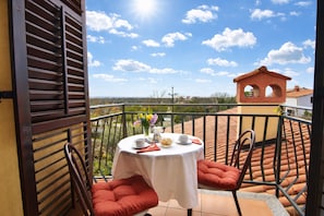 Ein Balkon mit Tisch für zwei Personen, einem Stuhl und Blick auf die Landschaft.