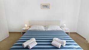 A neatly made bed with striped bedding, two pillows, and two bedside lamps. - Cozy Apartment With Shared Pool (Umag)