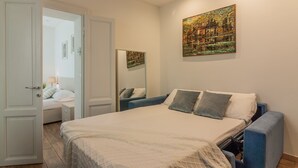 A bedroom with a bed, a blue armchair, a bedside table, a mirror, and a painting on the wall. - Dream Lake Home in Varenna (Varenna)
