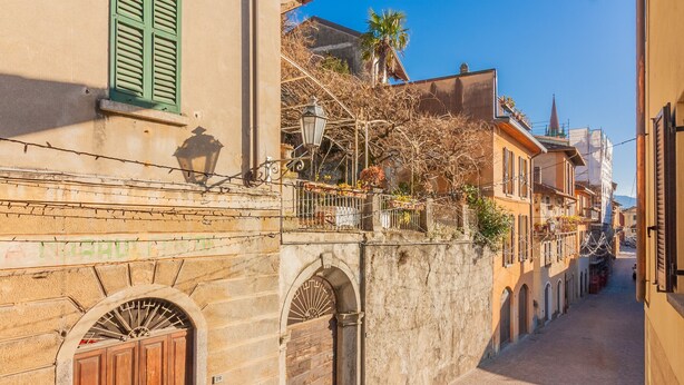 A narrow street with historic buildings, a stone wall, and a wooden gate. - Dream Lake Home in Varenna (Varenna)