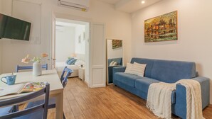 A modern living room with a blue sofa, a dining table with chairs, a white vase with flowers, and a painting on the wall. - Dream Lake Home in Varenna (Varenna)