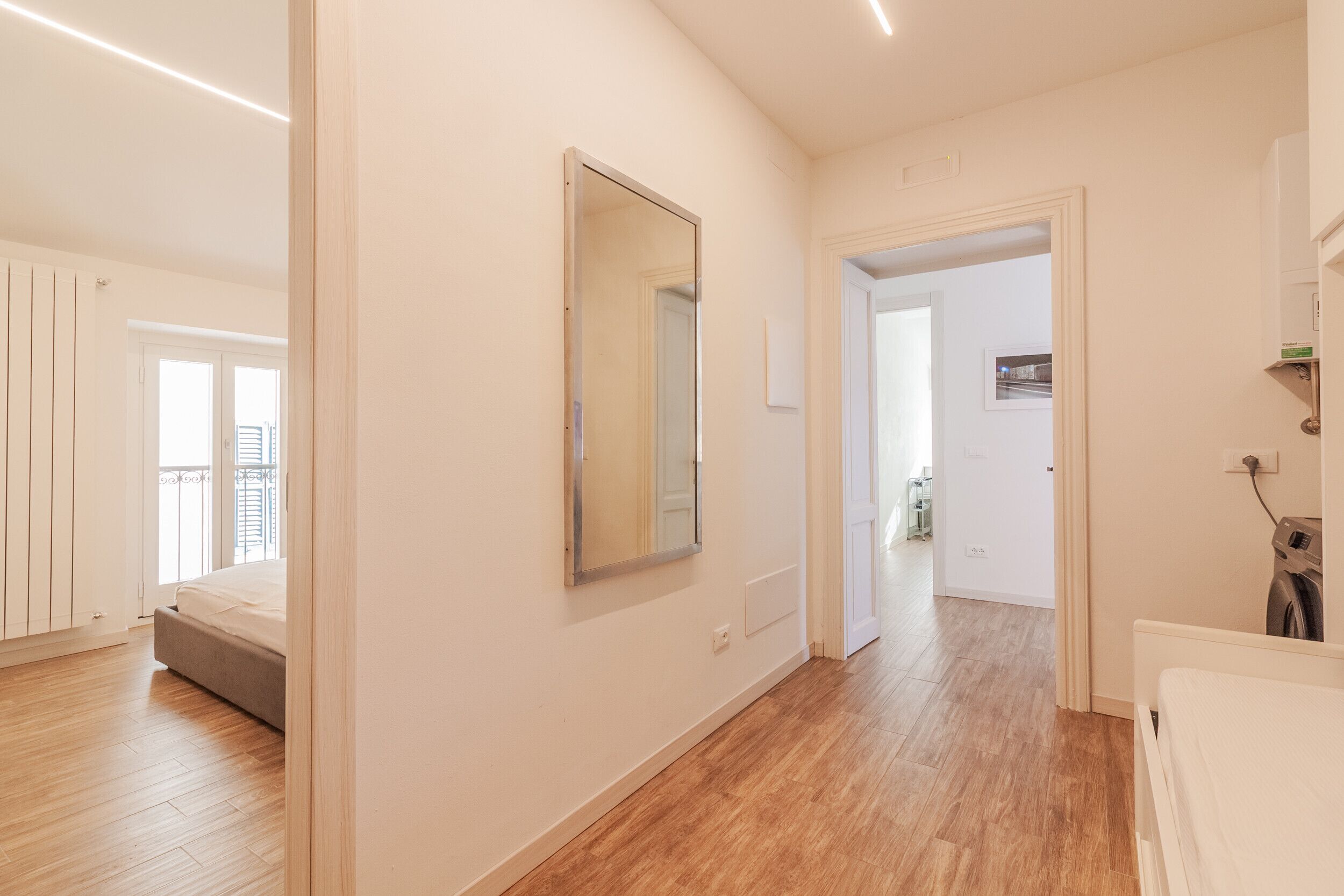Eine moderne Wohnung mit Holzboden, einem großen Spiegel, einem Bett und einer Waschgelegenheit.