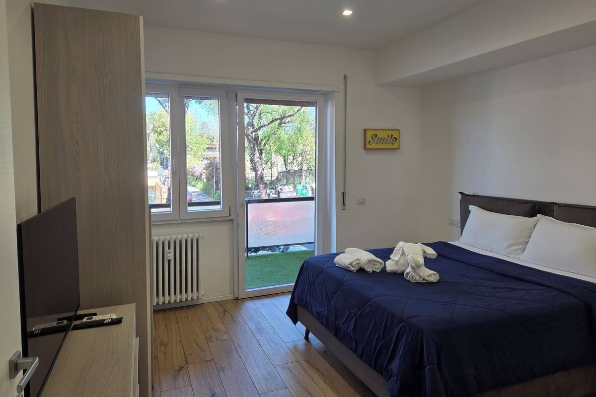 A bedroom with a bed, a television, a window, and a 'Smile' sign.