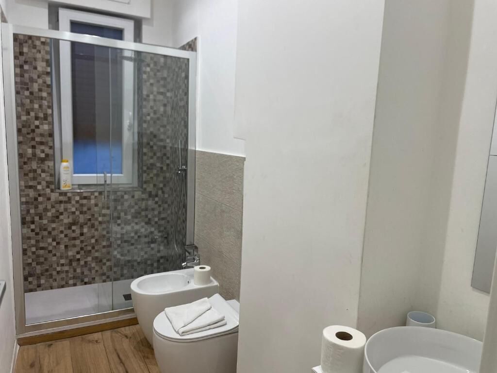 A bathroom with a glass shower enclosure, a toilet, and a sink.