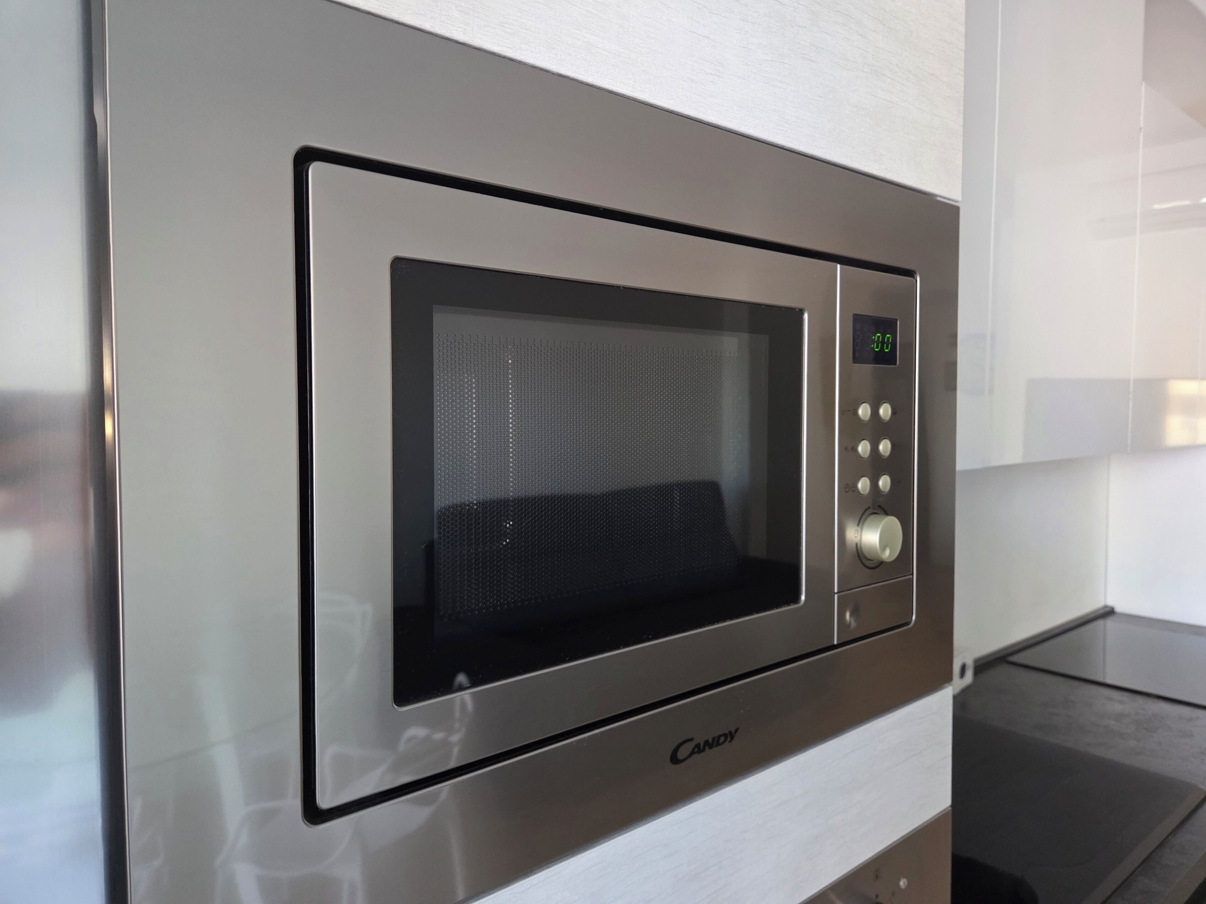 A microwave oven with a digital display and control panel, branded 'Candy.'