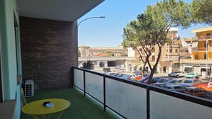 A balcony with a view of a street, a tree, and parked cars. - Imperatore suites (Rome)