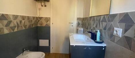 A bathroom with a bidet, a sink, and a mirror.