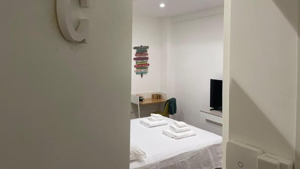 A modern hotel room with a neatly made bed, a television, and a stack of books on a shelf. - Imperatore suites (Rome)