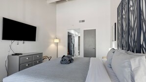 A modern hotel room with a large bed, a flat-screen TV mounted on the wall, a grey dresser, and a decorative wall panel. - Discover the Sedona Oak Creek Quiet Retreat, a cozy 2-bedroom condo in Village of Oak Creek. (Sedona)