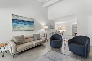 Ein modernes Wohnzimmer mit einer Couch, zwei Sesseln, einem Couchtisch und einem Bild an der Wand.