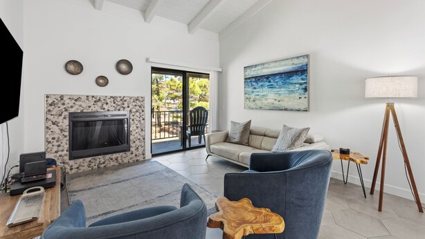 A living room with a fireplace, a sofa, a coffee table, and a painting on the wall. - Discover the Sedona Oak Creek Quiet Retreat, a cozy 2-bedroom condo in Village of Oak Creek. (Sedona)