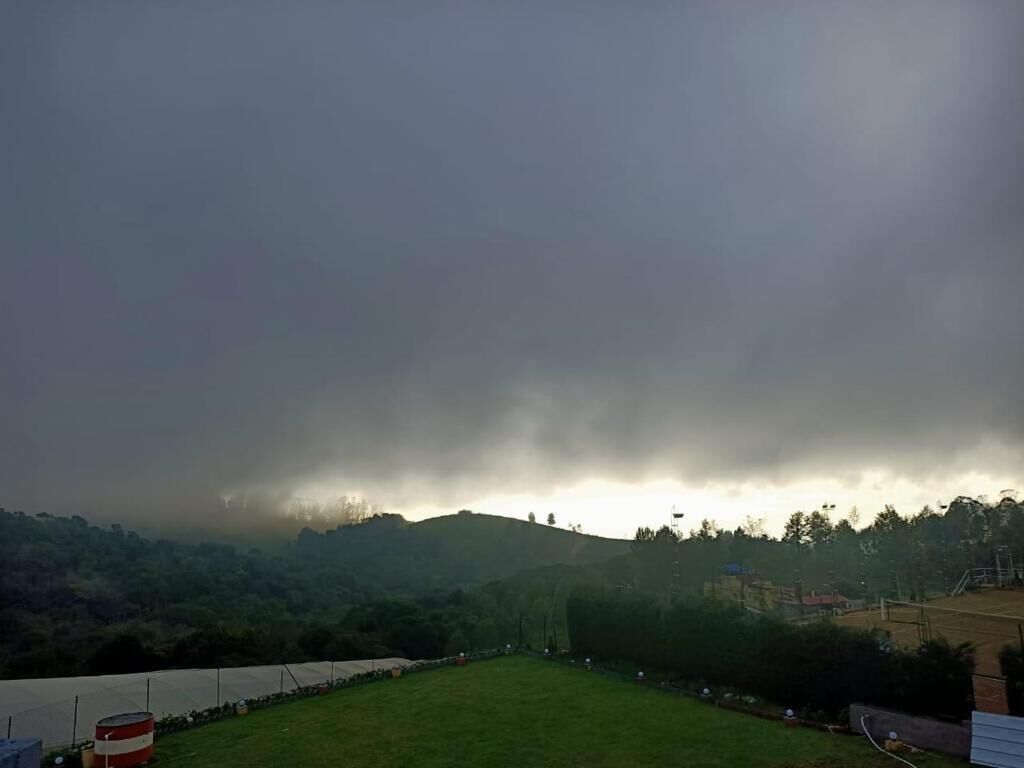 Ein grünes Feld mit einem Zaun und einem roten Fass im Vordergrund.