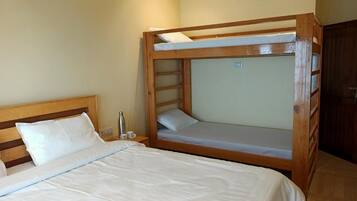 A room with a bunk bed, a single bed, and a nightstand with a lamp.