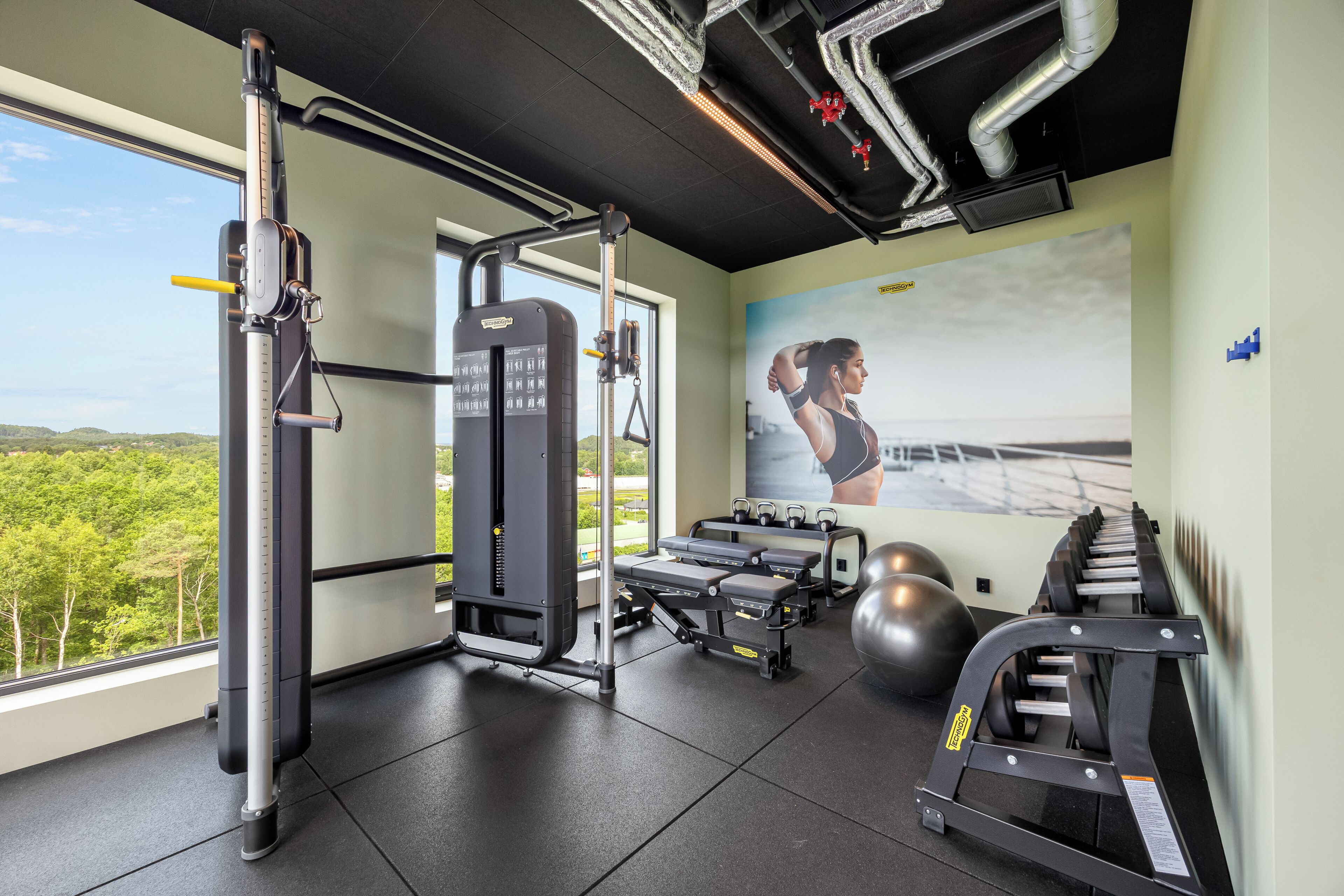 A gym with exercise equipment, a large window, and a motivational poster.