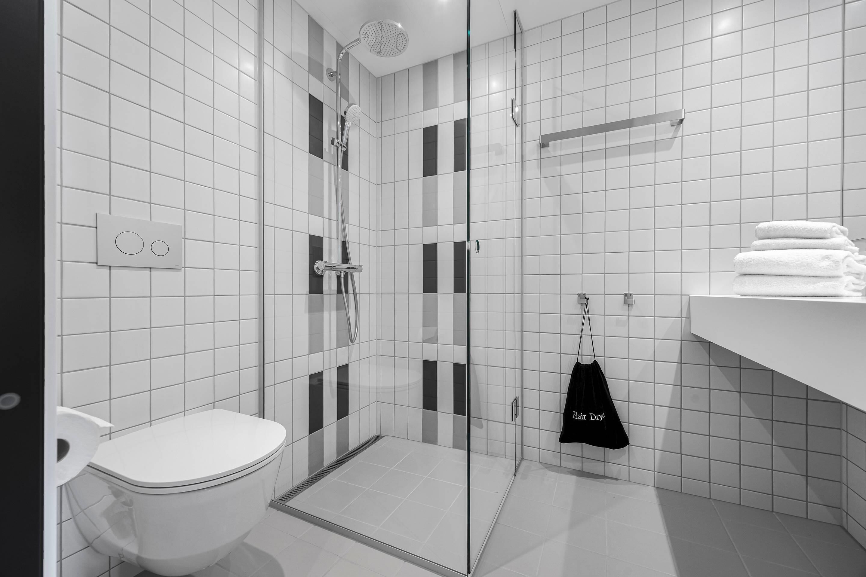 Une salle de bain moderne avec une douche à parois de verre, des toilettes et un porte-serviettes avec des serviettes pliées.