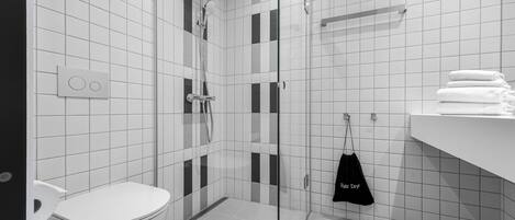 Une salle de bain moderne avec une douche à parois de verre, des toilettes et un porte-serviettes avec des serviettes pliées.