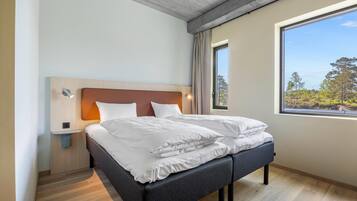 A modern bedroom with a bed, bedside table, and a window with a view.