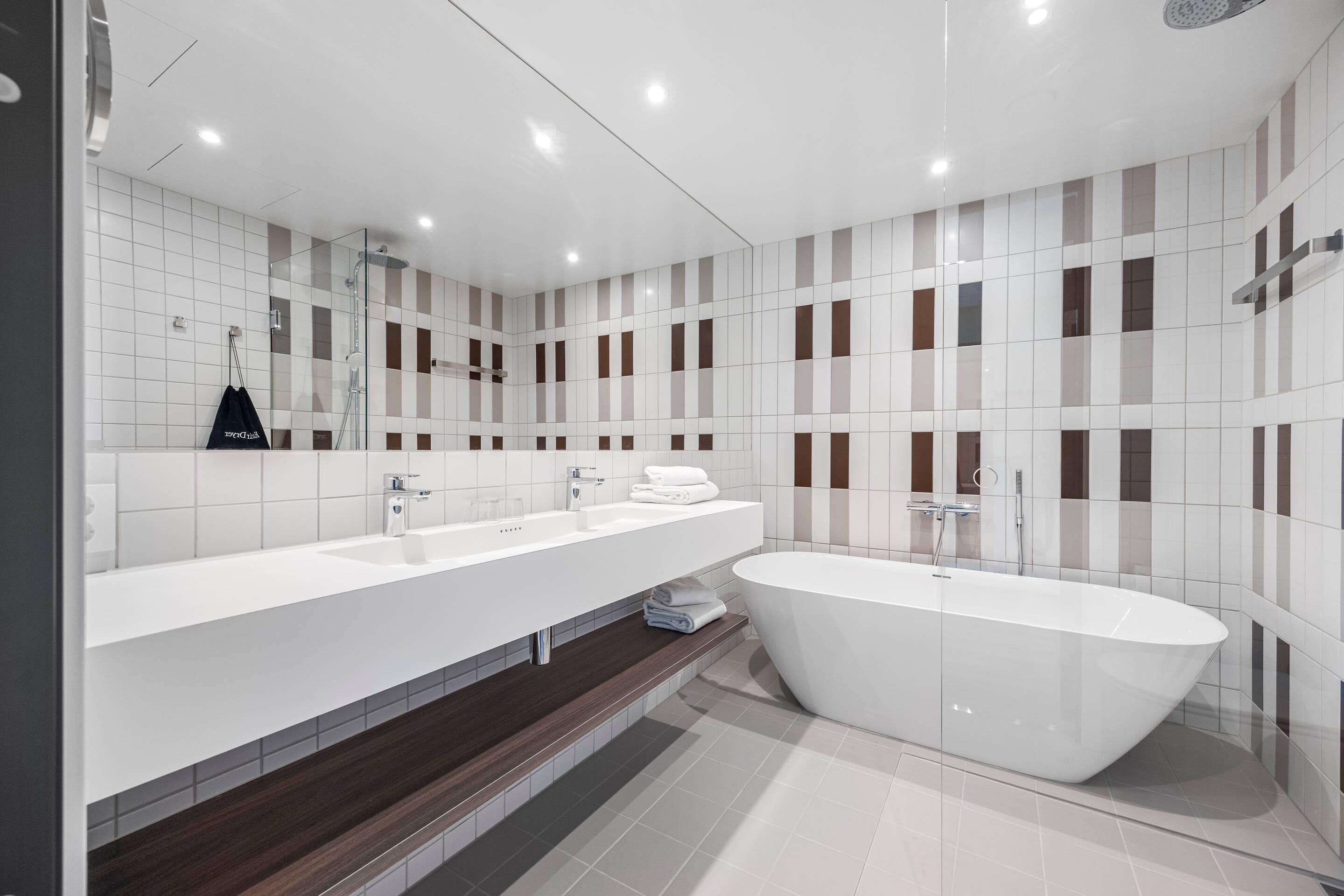 Un baño moderno con una bañera grande, dos lavamanos y un espejo.