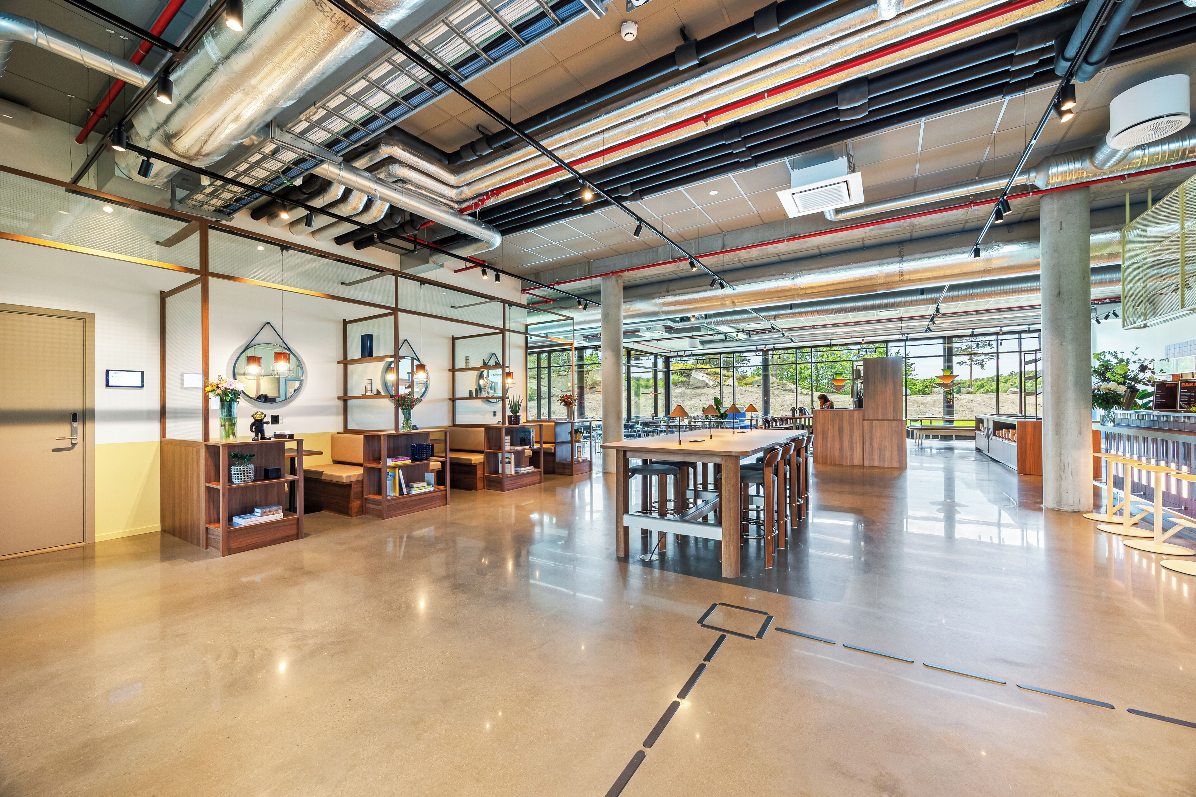 A spacious indoor area with a polished floor, wooden furniture, and large windows allowing natural light.