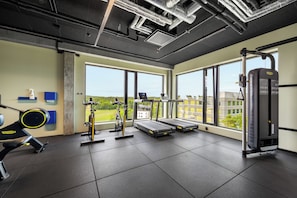 Een fitnessruimte met loopbanden, een hometrainer en een krachttrainingapparaat.