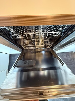 An open dishwasher with stainless steel interior and a metal rack. - Cozy 2BHK with Patio Waterloo LM01 (London)