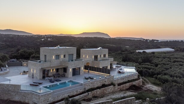 A modern villa with a pool, outdoor seating, and a view of the surrounding landscape. - Luxury carob tree villa near Almyrida beach with private pool! (Gavalohori)