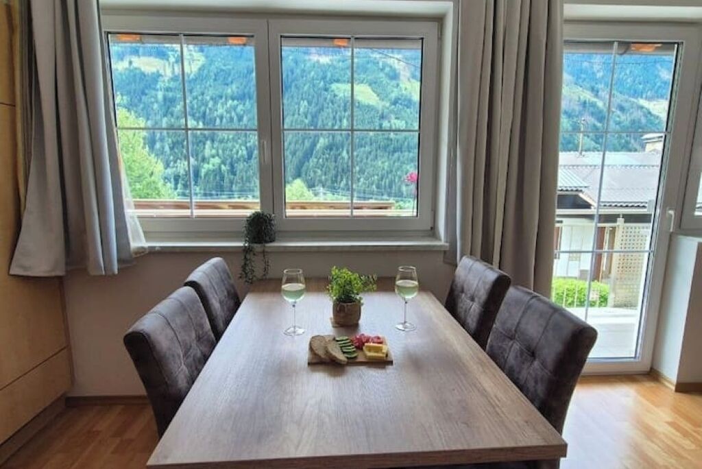 A dining table with two chairs, a plant, and a fruit platter.
