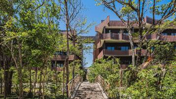 Un chemin menant à un bâtiment doté de nombreux balcons, entouré d’arbres et de verdure.