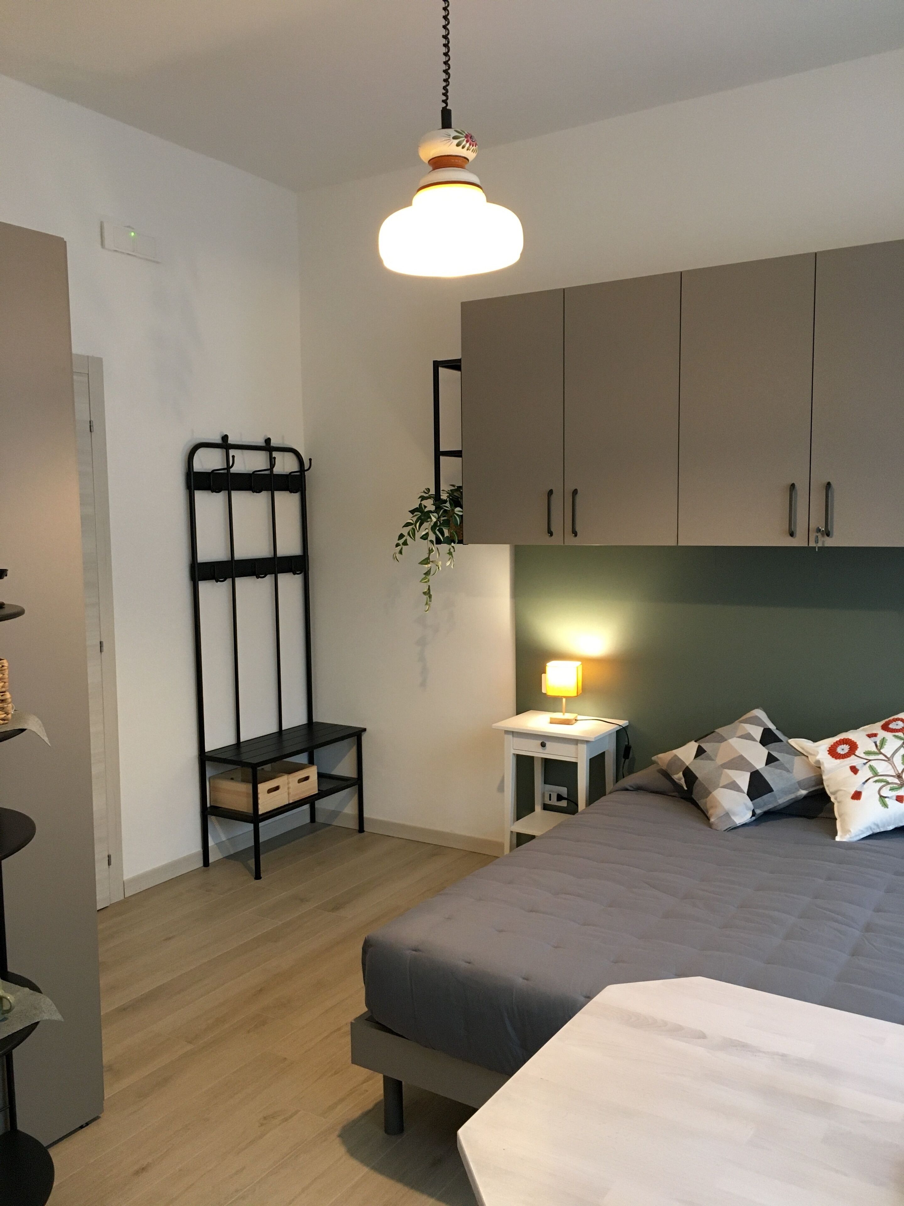 A bedroom with a bed, bedside table, lamp, and wardrobe.