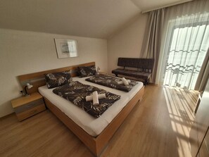Une chambre d’hôtel avec un grand lit, une table de chevet avec une lampe, un banc et un téléviseur.